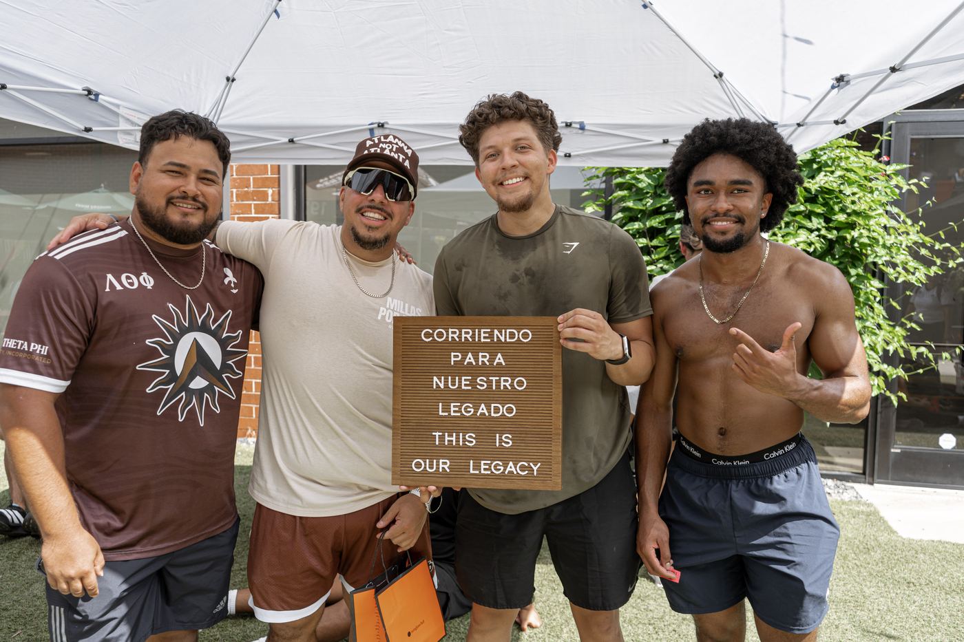 Four runners with their arms around each other, holding the letterboard after finishing.