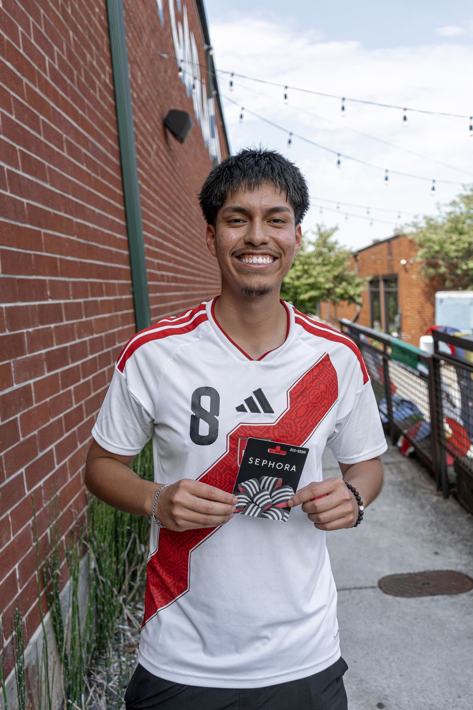 A runner in a Peru jersey holding up a Sephora gift card won in the raffle.