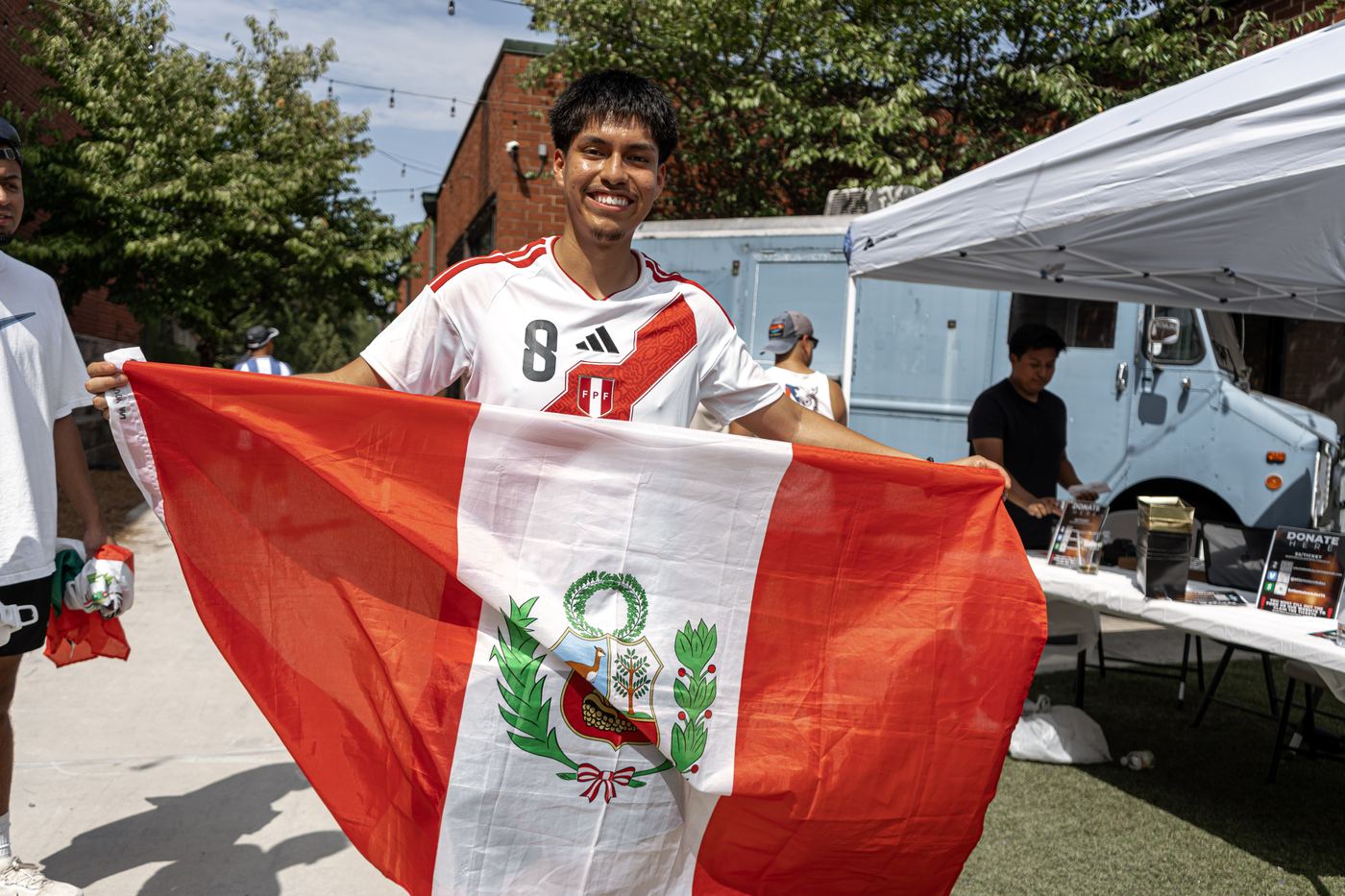 A runner holding a Peru flag open wide across the courtyard.