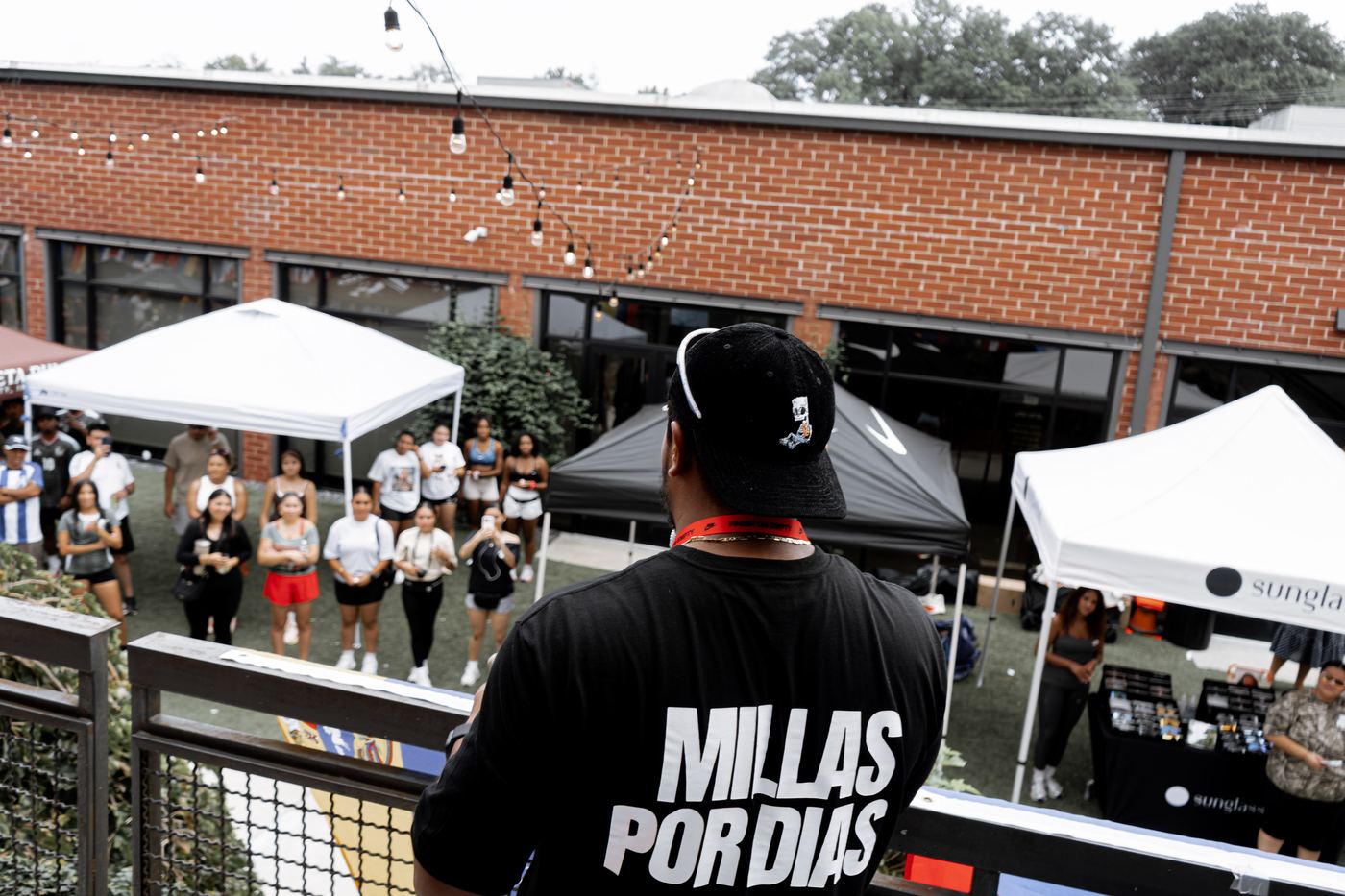 A run club organizer in a Millas Por Dias shirt addressing the crowd from the balcony above the courtyard.