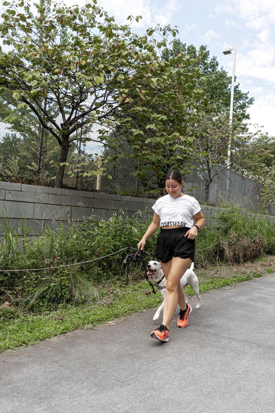 A runner jogging the trail with a dog on a leash alongside.