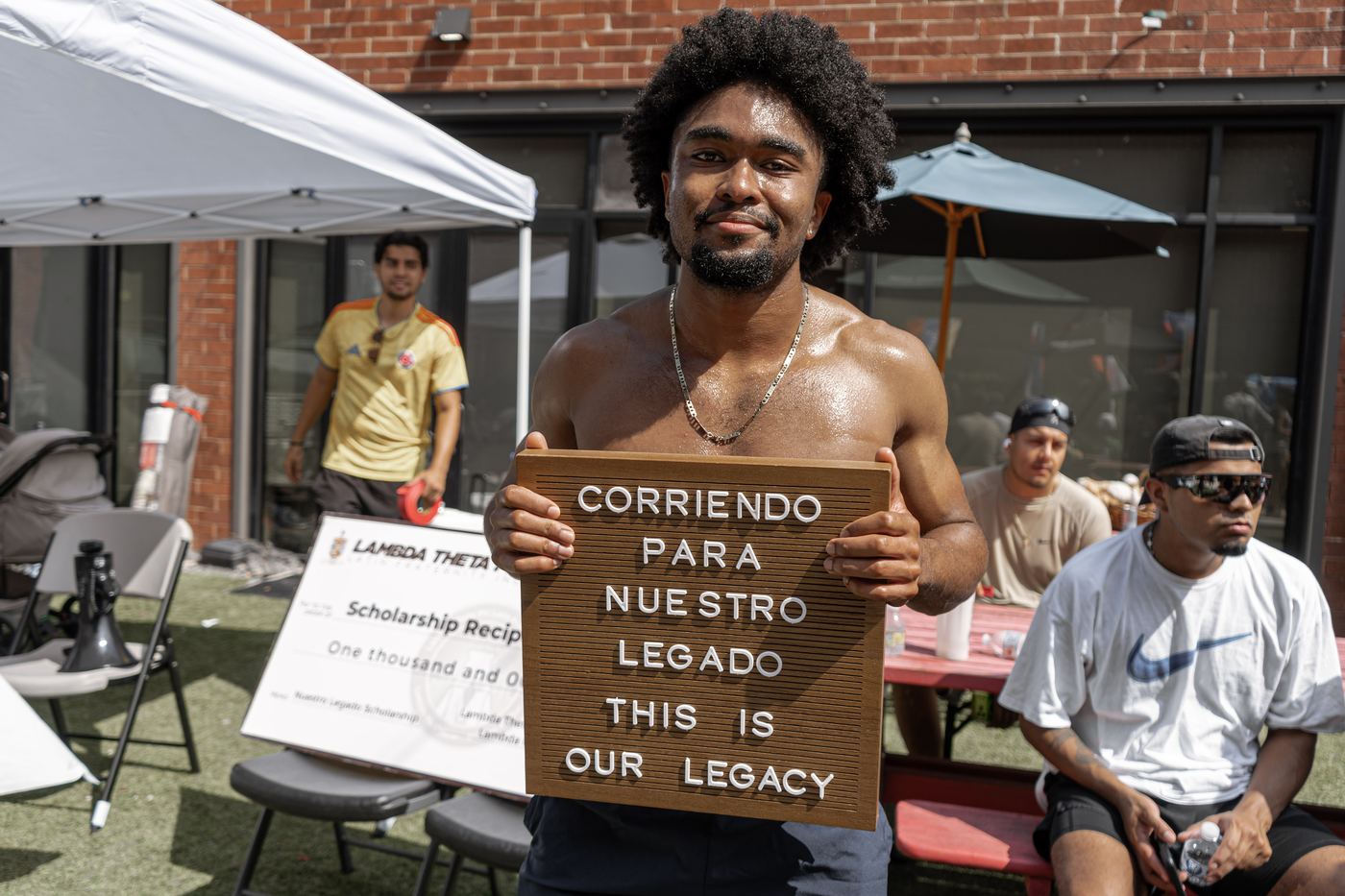A runner holding the letterboard in front of the oversized thousand dollar scholarship check at the finish line festival.