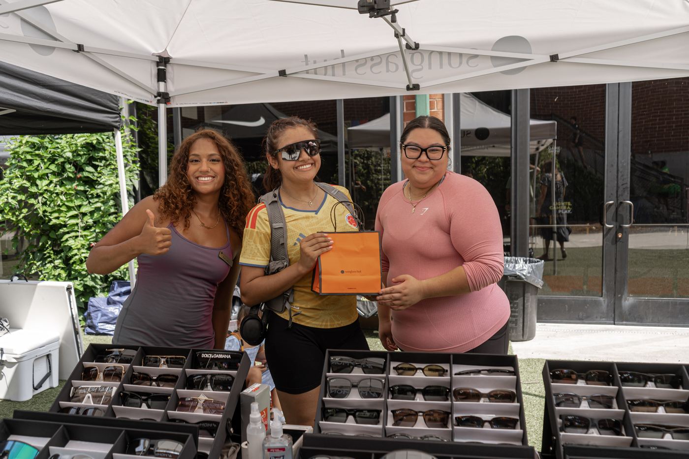 A runner collecting a prize at the Sunglass Hut table, between two of the staff.