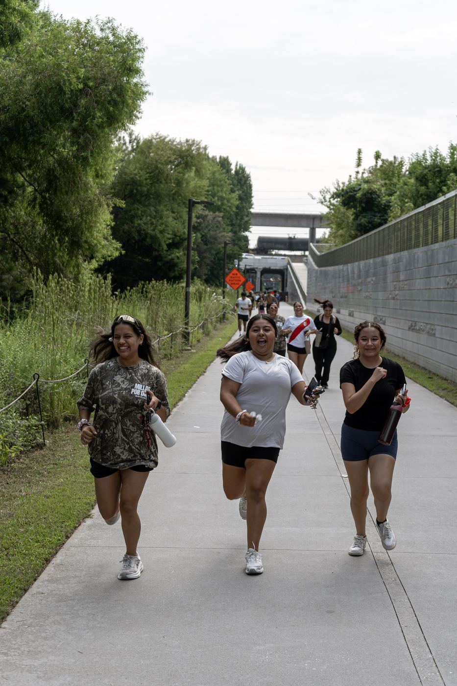 Three runners coming up the trail toward the camera, mid stride and laughing.