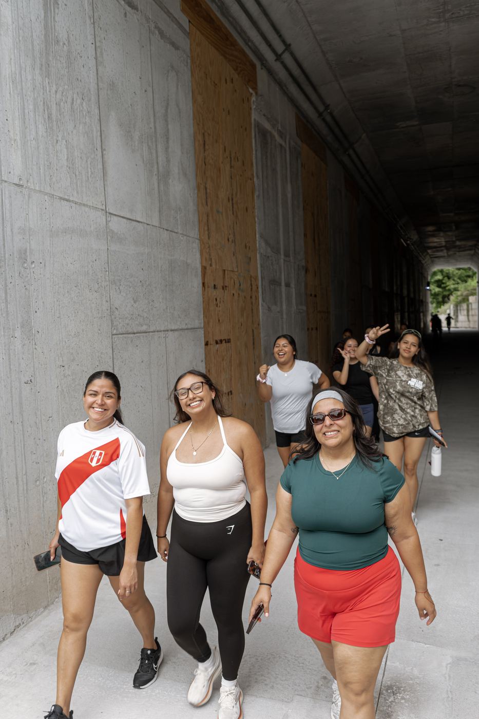 Six walkers coming through a concrete underpass on the BeltLine, laughing.